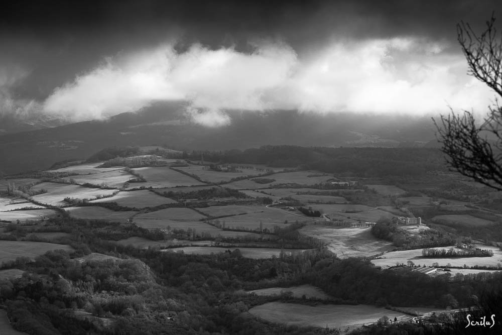 Prés et forêts sous un ciel nuageux. Le château se réserve la place au soleil.