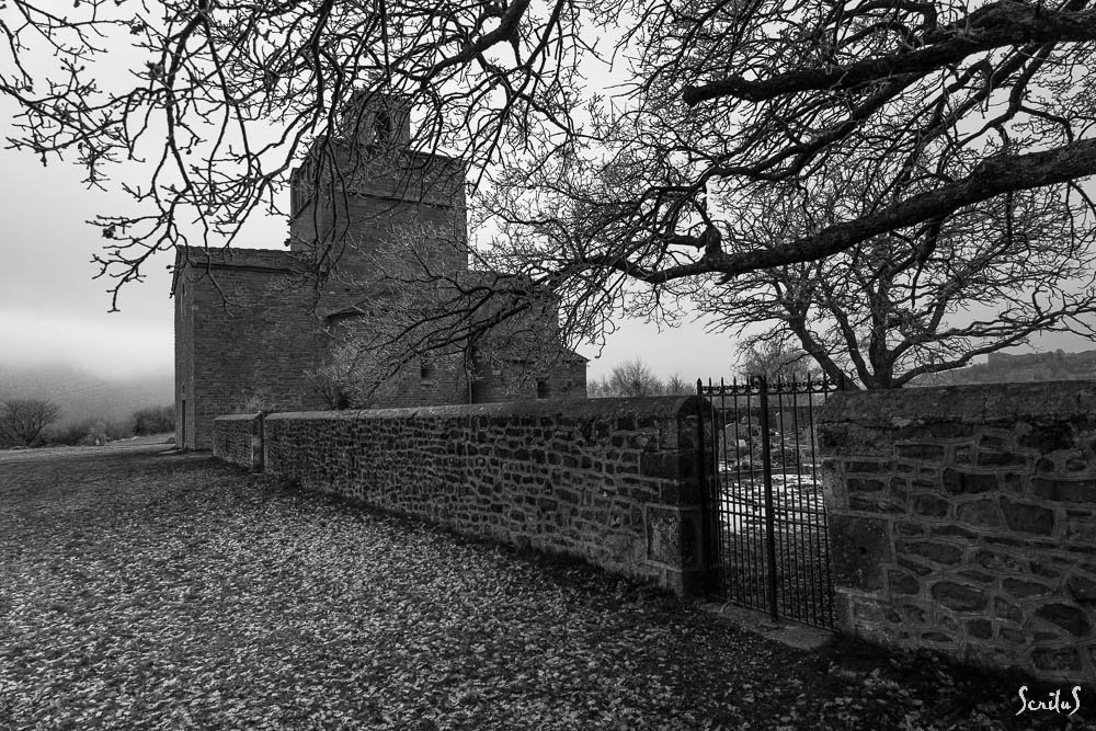 Chapelle et mur de cimetière sous un ciel plombé. Beauté du lugubre.