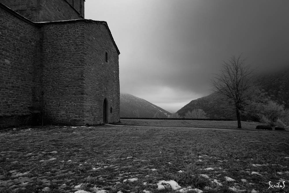 Chapelle, arbre givré et vallée sous un ciel plombé. Beauté du lugubre
