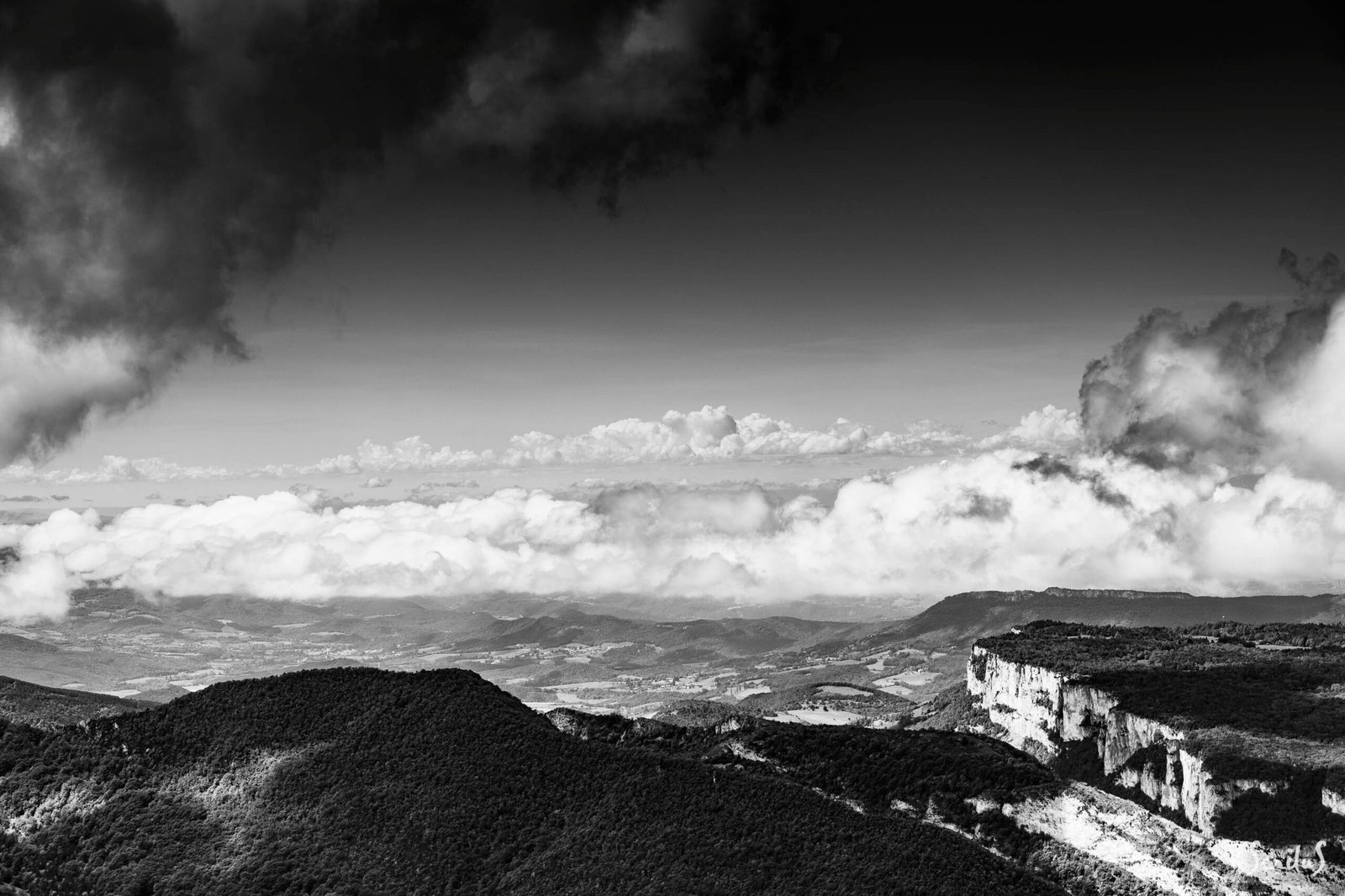 Paysage de vallon et de falaise sous un ciel très nuageux